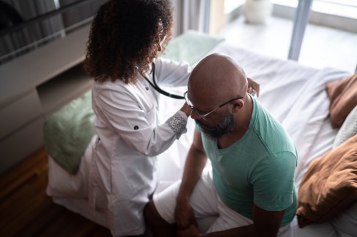 Een arts luistert tijdens een huisbezoek naar de hartslag van een patiënt